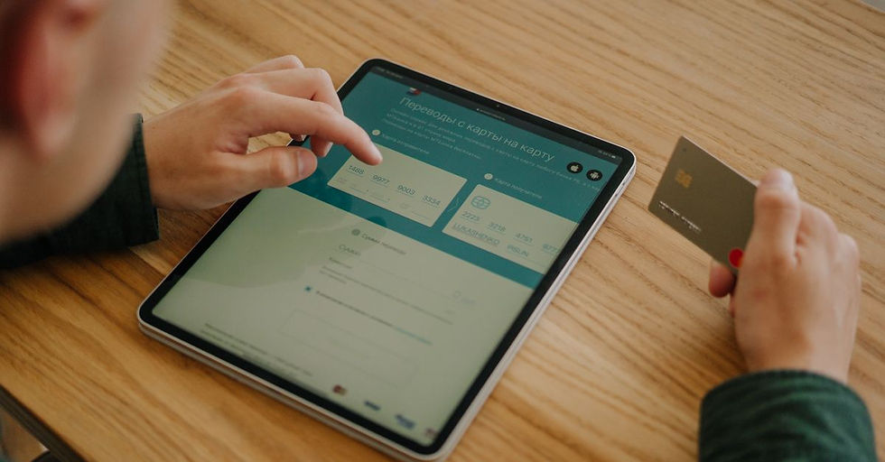 Person making an online payment using a tablet and credit card on a wooden desk.