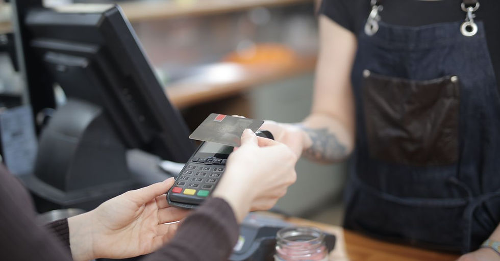 Close-up of customer and cashier during a credit card transaction at a store counter indoors.