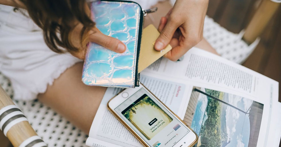 Close-up of woman using credit card with smartphone and magazine