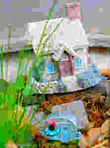 Fairy garden cottage with little old fashioned camper in moss, rocks, grass
