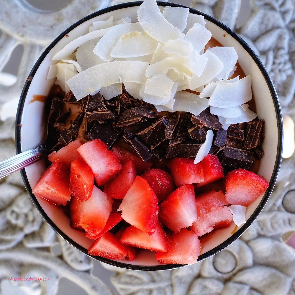 strawberries, chocolate, coconut in a smoothie bowl on a table