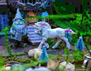 Fairy garden with garden gnome, unicorn, bottle brush trees and castle in the background