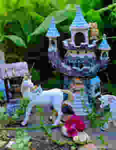Fairy garden castle with unicorns, wishing well, flower surrounded by greenery