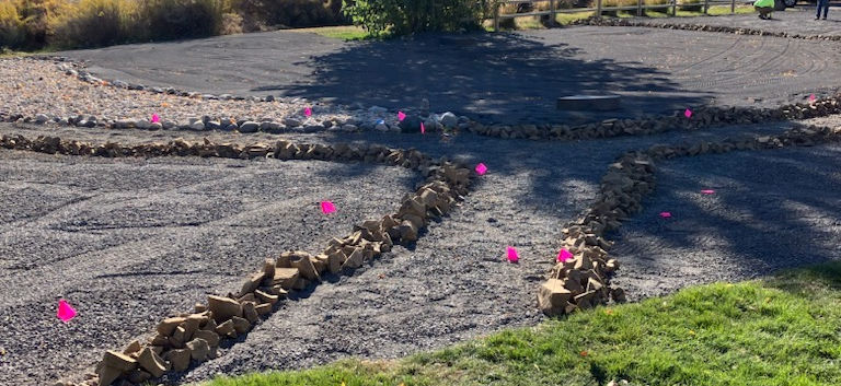 Rock pathway and pink flags indicating where plants will go