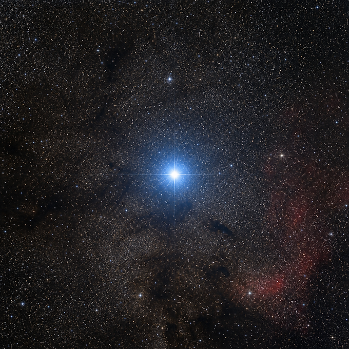 Deneb als grell blauweiß leuchtender Stern im dichten Sternfeld des Schwanes, mit kontrolliertem Lichtsaum, dunklen Staubbändern der Milchstraße und nur zartem Nebelglimmen im Hintergrund.