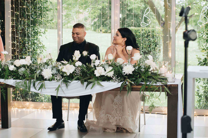 Bride and groom sitting at a floral wedding table