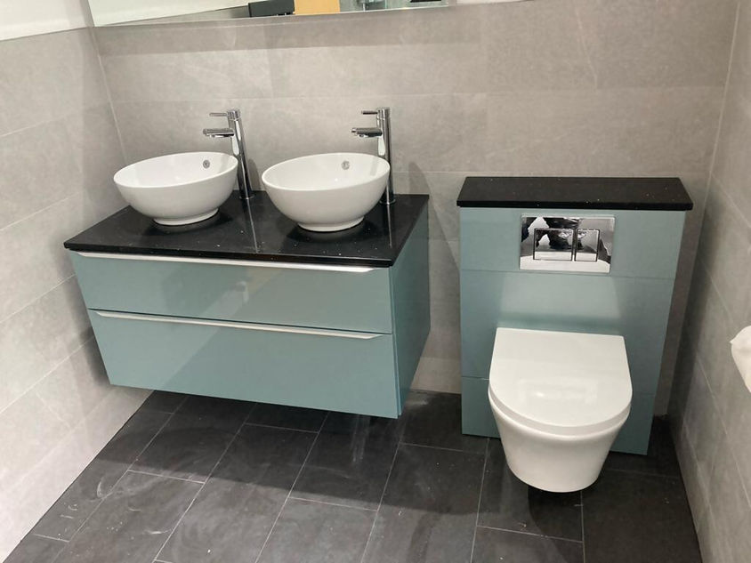 Teal green bathroom cabinets, two sink bowls and toilet