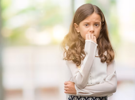 An anxious young girl looking worried and biting her fingernails