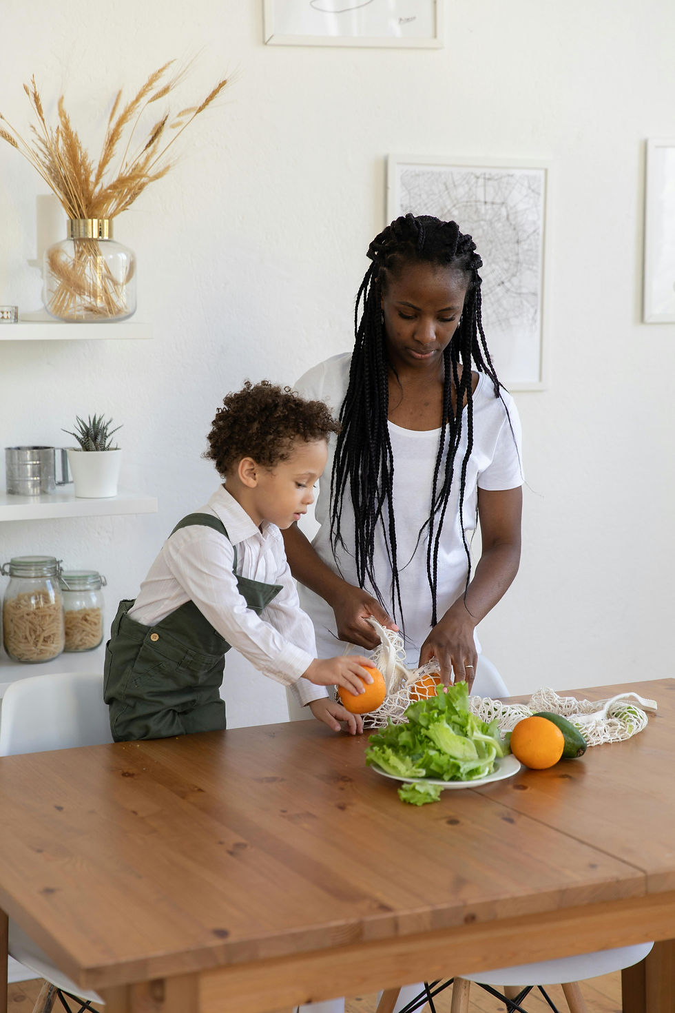a mother and young son putting fruits and vegetables on a plate