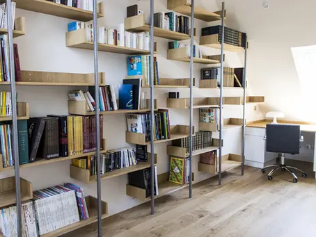 Bureau-bibliothèque sous combles, optimisé avec des rangements intégrés, une bibliothèque asymétrique et un coin détente.