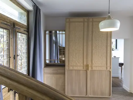 Meuble d’entrée sur-mesure en chêne clair et cannage, optimisant l’espace avec rangements intégrés et cache-radiateur.