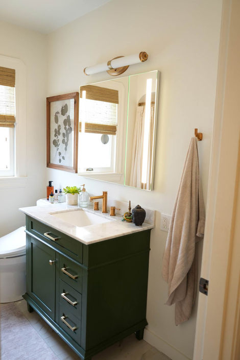 white bathroom with green cabinets and white sink 