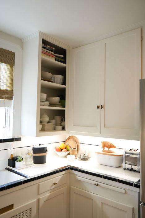 Kitchen counter with toaster and fruit and white cabinets above and below counter 