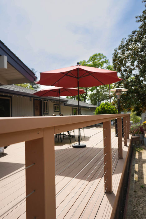 tan wooden outdoor deck railing with red umbrella on deck 