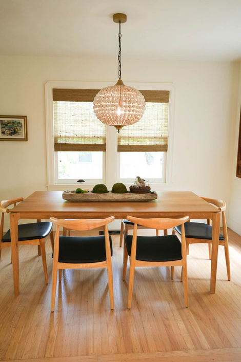 dinning room with wooden table and chairs with black leather cushion  and chandelier hanging over table 
