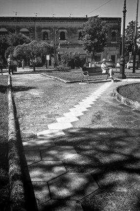 Black and white photograph of a hexagonal paved path running diagonally through a park in Maglie