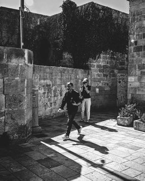 Black and white photograph of two photographers from the group crossing a sunlit courtyard in Maglie