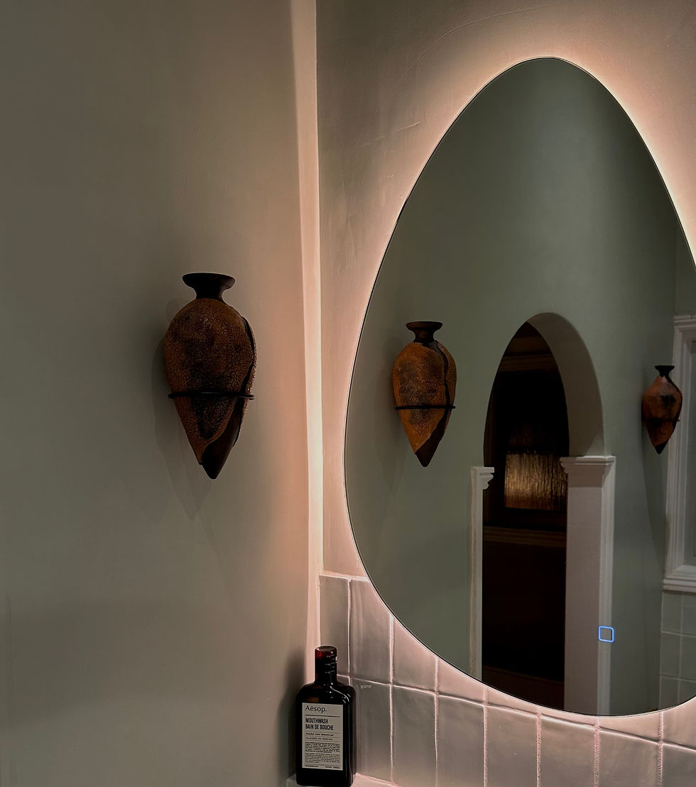 Peaceful bathroom, with glowing mirror and ceramic wall art.