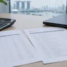 Rules of origin Singapore check: a bill of materials, a printed tariff schedule and a calculator on an office desk