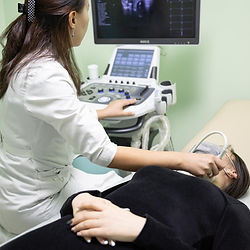 Technician performing thyroid ultrasound on patient