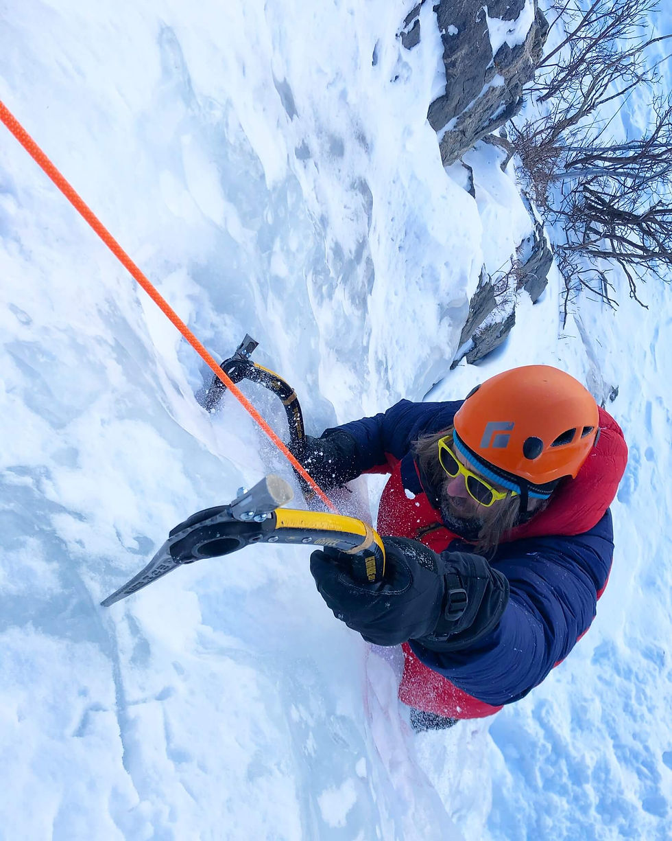 Ice climber swinging an ice tool at Lincoln Falls