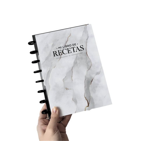 Mano sosteniendo un cuaderno con la frase "Mis Libros de Recetas"