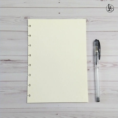 Hoja de papel beige con bolígrafo transparente sobre fondo de madera blanca.