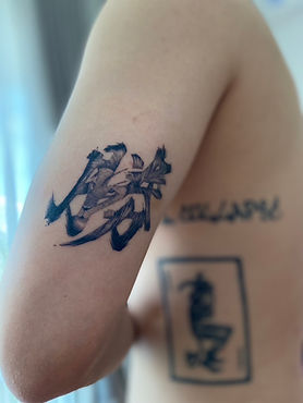 Healed Chinese character with lion inside tattoo on the upper arm by Baan Khagee Tattoo Chiang Mai, Thailand