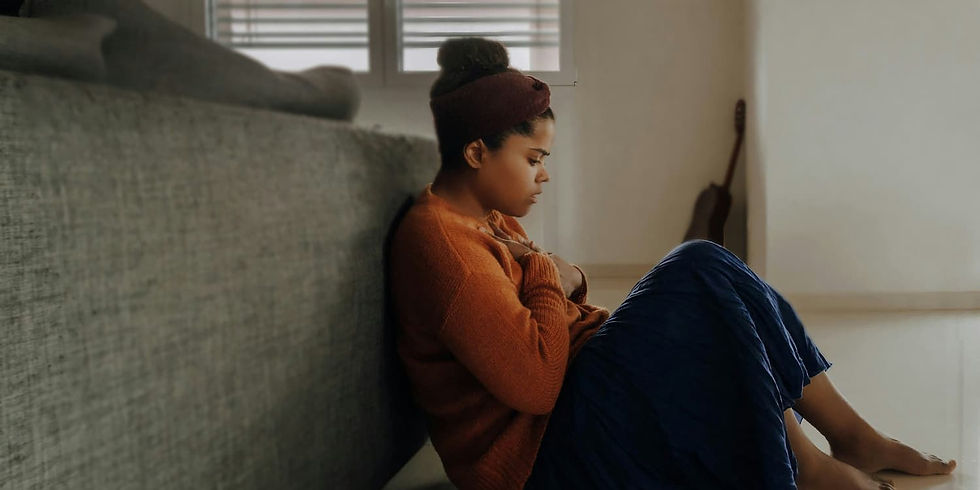 Jeune femme assise au sol, la main sur la poitrine, représentant les manifestations physiques de l’anxiété.