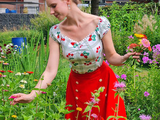 a girl in a cottagecore dress picking flowers