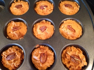 muffin tin with muffins and pecan on top
