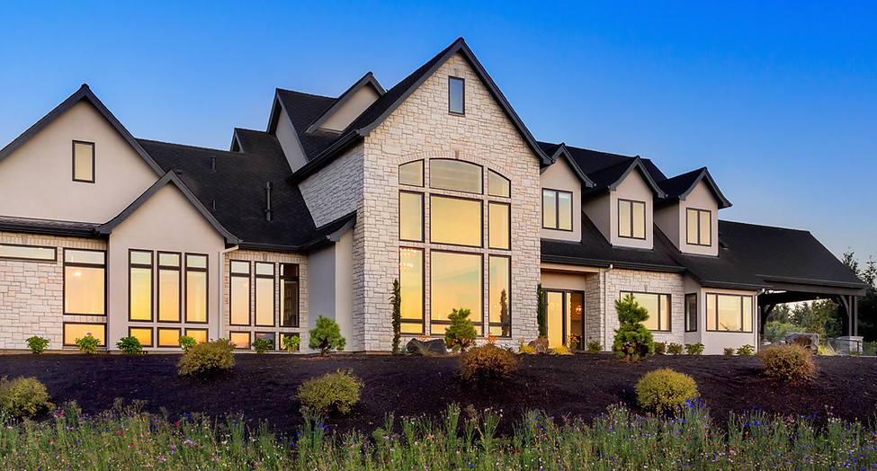 newly built custom home with black windows, lit up in the evening time