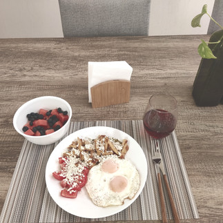platillo de huevos estellados, vaso de jugo y plato de fruta en comedor