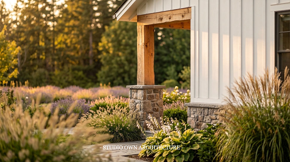 White farmhouse porch with wood post and stone base, surrounded by golden ornamental grasses and purple flowers at sunset