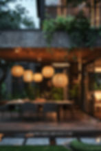 Outdoor dining area with hanging lanterns above a table set for dinner. Lush greenery surrounds the modern space.