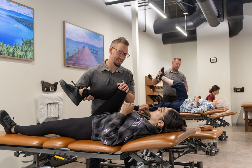 A physical therapist assists a female patient with leg stretches on an examination table.