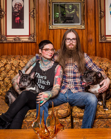 Couple sitting arm in arm with their dogs looking into the camera