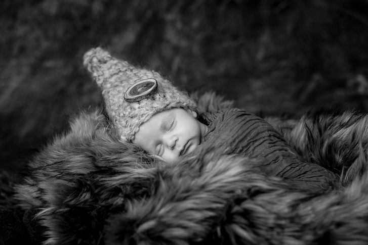 Studio shot of newborn baby sleeping in a nest of fur wearing gnome hat
