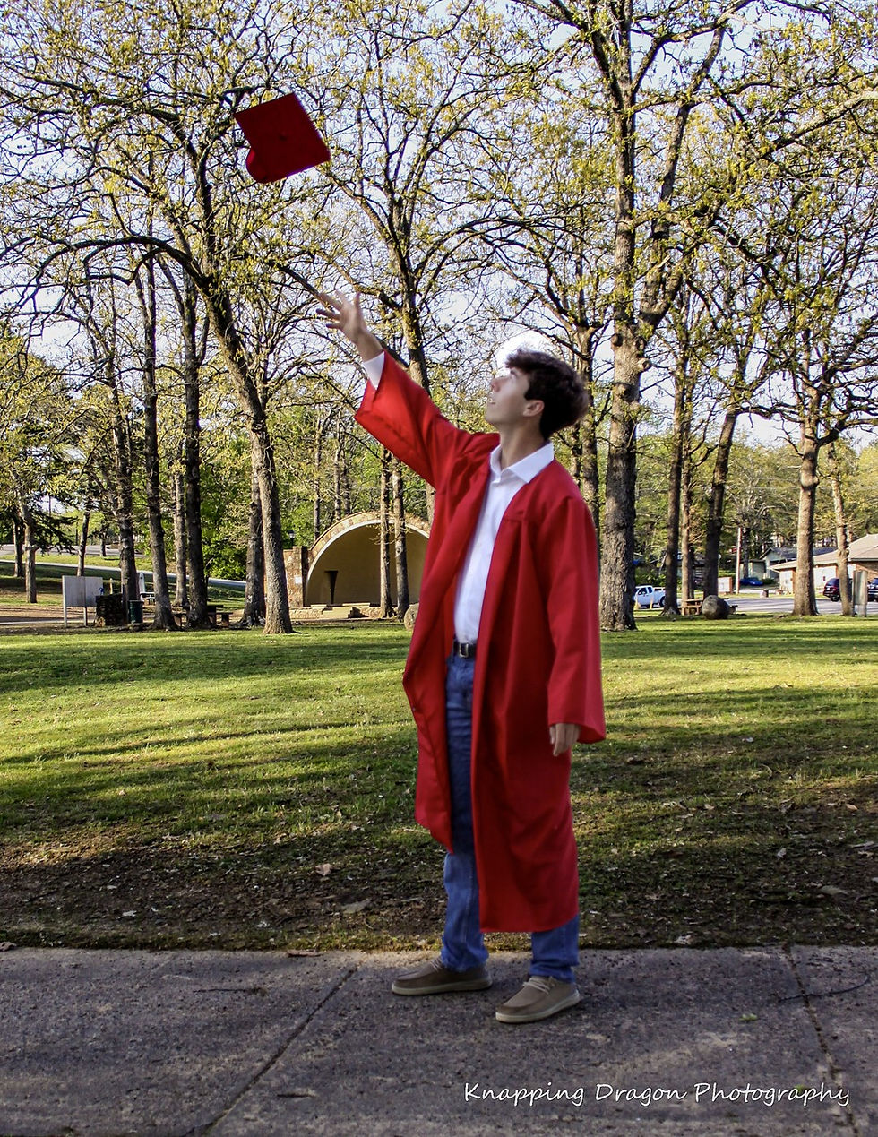 A Heber Springs High School graduate joyfully tosses his cap in the air at Spring Park, captured by Knapping Dragon Photography.