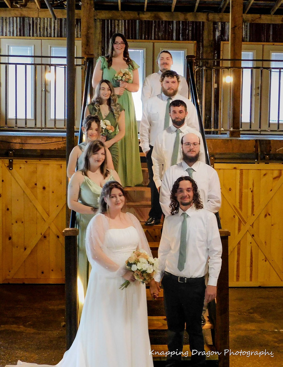 A joyful wedding moment captured in Judsonia, Arkansas, featuring the bride and groom surrounded by their smiling bridal party on a rustic staircase. Photography by Knapping Dragon Photography.
