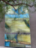 Large tile mural of landscape on brick wall under tree branches