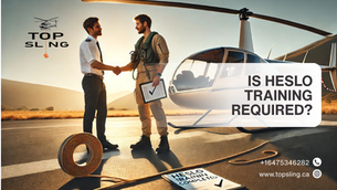 Pilot completing HESLO helicopter external sling load training, receiving instructor approval with signed logbook and certificate beside a training helicopter.