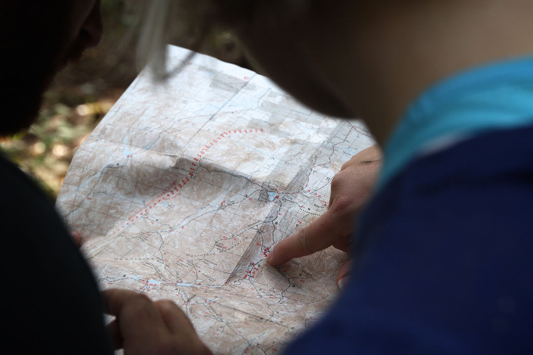 Person pointing to a paper map for navigation and tracking.