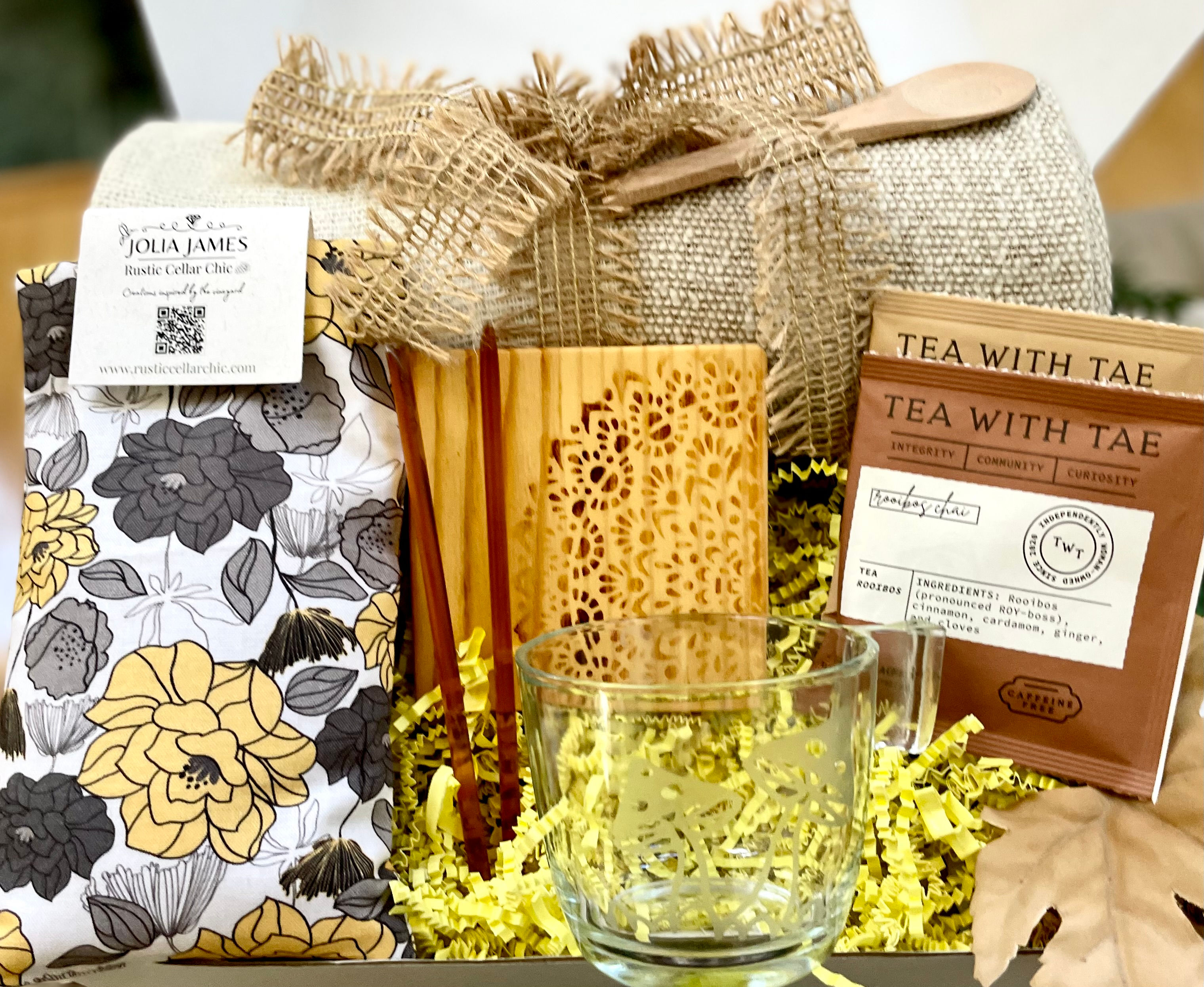 Deluxe tea lover' gift set with tea, glass etched mug, coaster, blanket, wooden spoon, lavender eye pillow, and honey sticks.