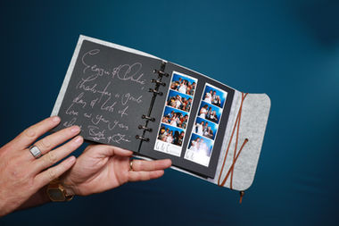 Someones hands holding up a signed photo booth guest book.