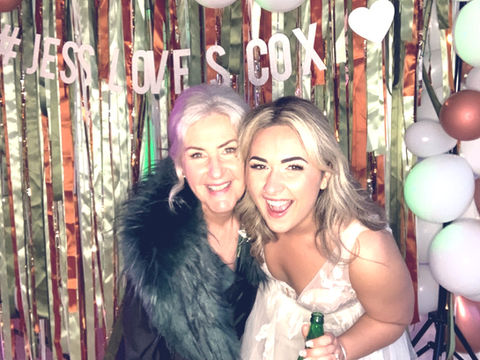 Mum and daughter taking cute shot at daughters wedding. Photo booth picture.