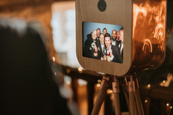 CopperNob photo booth screen showing group of male wedding guests in black suits.