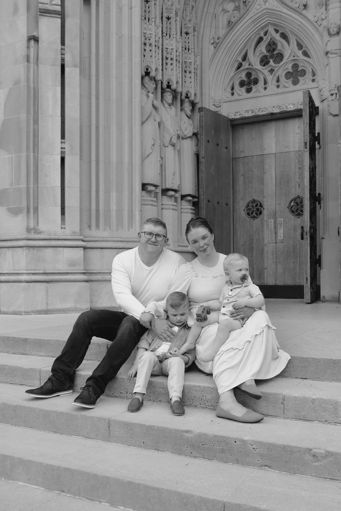 Black and white family photo sitting on steps in front of ornate building