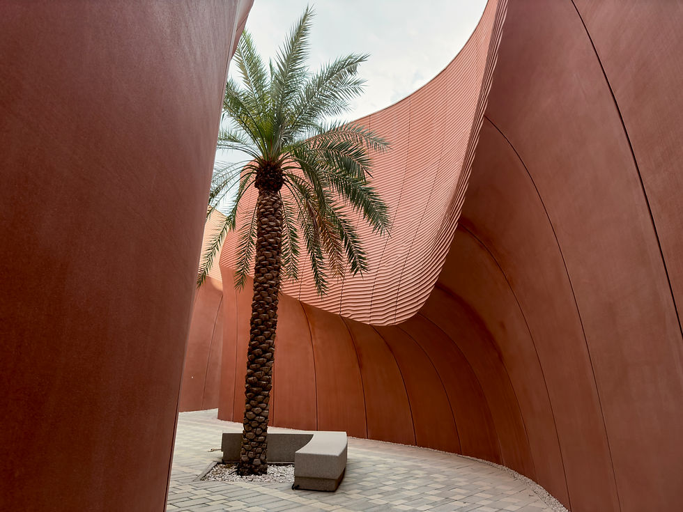 Modern architectural walkway in Dubai with curved terracotta walls and a tall palm tree in the center