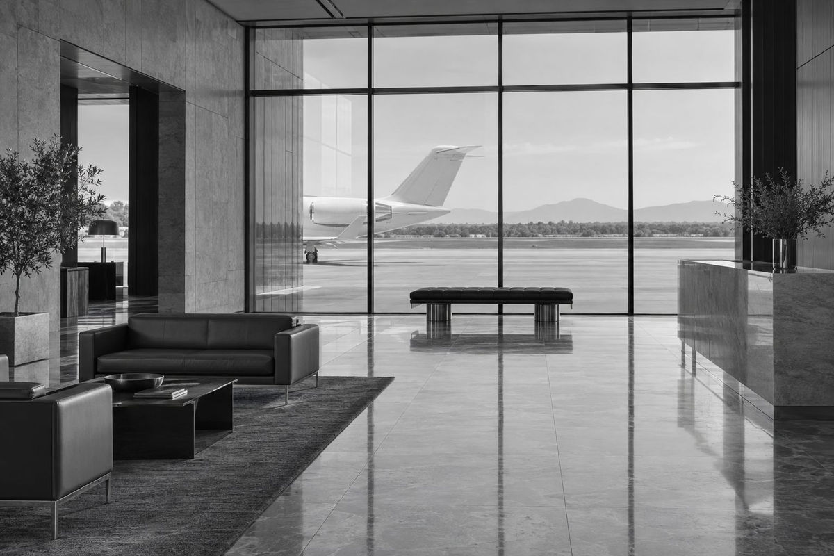 The glass front of a private aviation terminal with an aircraft tail beyond